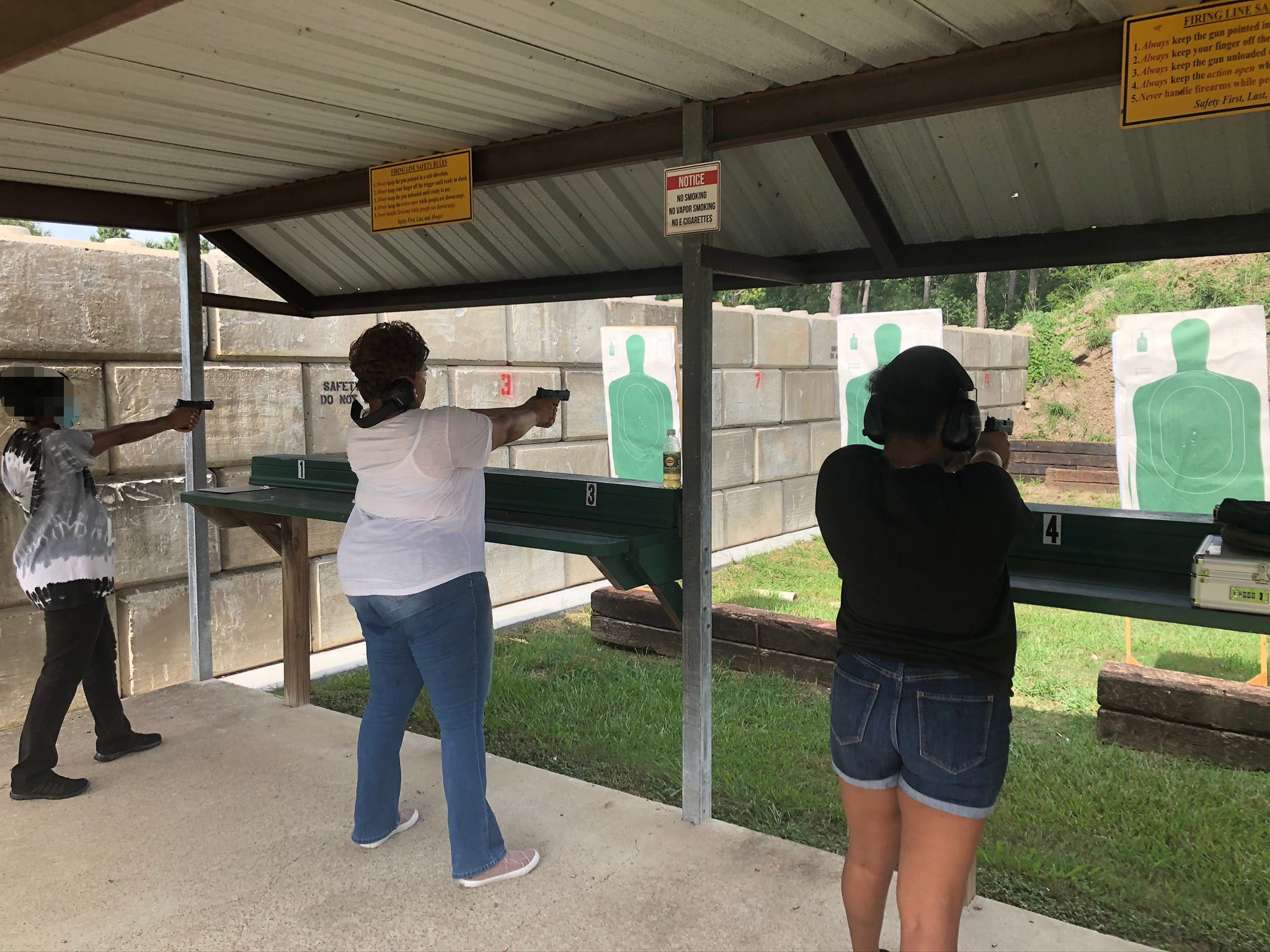 Three women at a shooting range aiming guns at targets