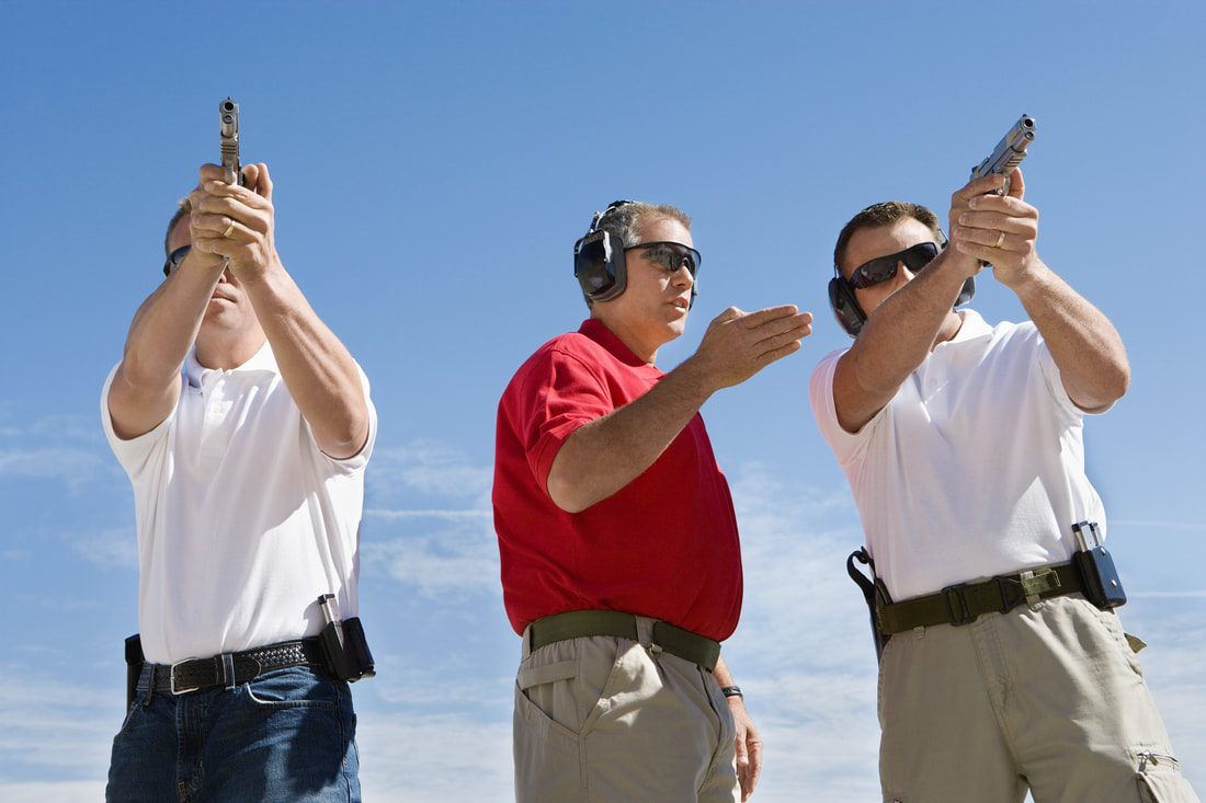 An instructor teaching two men holding guns